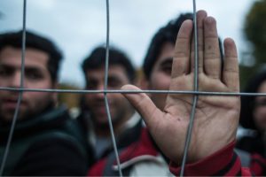 Migrants look through the fence as they wait to cross the Slovenia-Austrian border in Spielfeld, Austria, on October 22, 2015. 